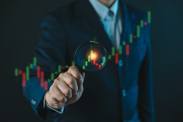 Businessman hold a magnifying glass for concept of stock market trading analysis, Digital...