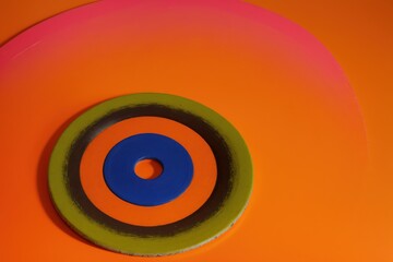 A colorful frisbee with a pastel orange background and room for words