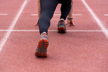Focused on the legs of a professional sportsman in a starting position, poised to run along the...