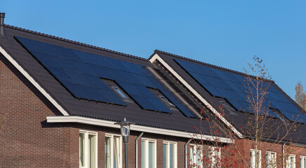 Fototapeta premium Solar panels on the roofs of houses on a sunny day, blue sky 