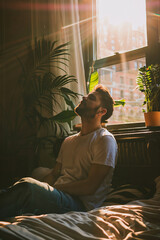 A contented man is seen engaging in relaxation exercises within the comfort of his large and well lit apartment.