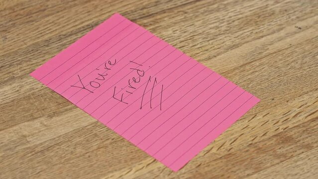 Hand writing "You're Fired" Note pad, lay-off job loss, unemployment, disciplinary action, HR Human resources, 4K