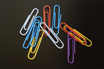 Obraz premium colored paper clips on a black background