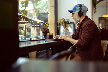 Modern senior man working remotely in a cafe setting