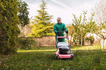 Man mowing the lawn in a sunny garden
