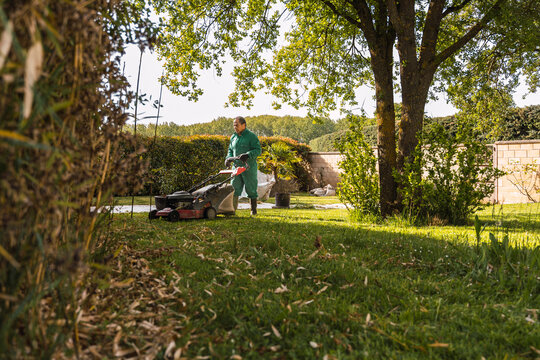 Man mowing a lush green lawn in a serene garden