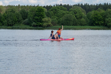 Two young people doing water sport on sap board in the wide river, adventure active lifestyle