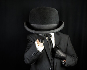 Portrait of British Gentleman in Dark Suit and Leather Gloves Holding Bowler Hat. Vintage Style and...
