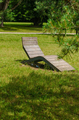 Empty beach lounger on green grass in a park on a summer day. High quality photo