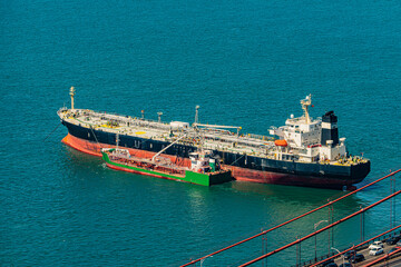 Oil tanker receiving fuel from bunkering tanker in the port