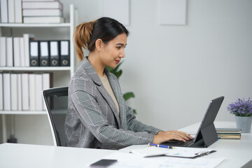 Young professional woman working on a laptop in modern office setting. Organized workspace and focused business environment.