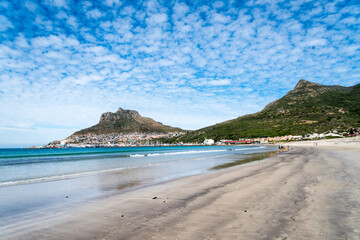 Hout Bay beach and scenic view of distant harbour and mountains on a summer day with mackerel sky in Cape Town, South Africa