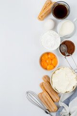 Ingredients for preparing the Italian dessert tiramisu. Savoiardi cookies, mascarpone, yolks, coffee, cream and cocoa on a light background, top view.Free space for copying.