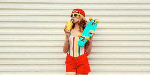 Summer stylish relaxed modern young woman with skateboard drinks fresh juice in colorful clothes