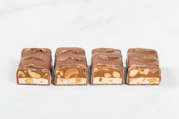 Candy bar. Nougat, caramel with peanuts, in milk chocolate. In the section.  Close-up