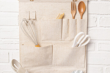 Wall hanging organizer with pockets for kitchen utensils on white wall background. Organizer for kitchen