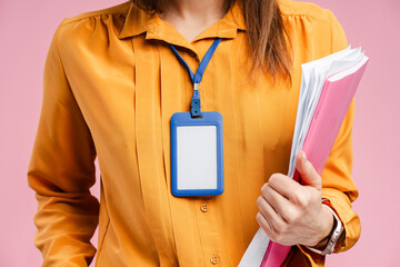 Portrait of businesswoman standing with id card around her neck, holding documents