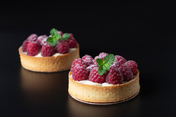 Tarts with fresh raspberries on black background