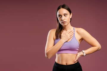 Obraz premium Tired young woman standing holding hand on her chest, resting after training, isolated