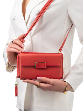 Stylish red leather clutch bag with gold accents and tassel complementing chic look of young woman in white outfit. Concept of luxury accessories and personal style elegance