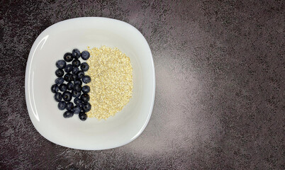 berries and oatmeal on a white plate stand on a textured background