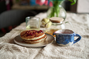 Simple pancake breakfast with jam and apple, tea served on a kitchen table. Simple life concept High quality photo