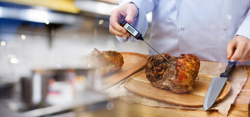 Cook measuring temperature of cooked meat on table.