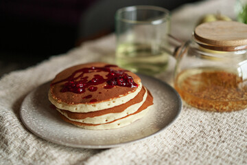 Simple pancake breakfast with jam and apple, tea served on a kitchen table. Simple life concept High quality photo