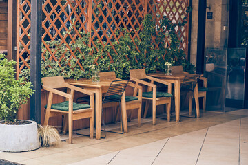 An empty cafe terrace with a wooden table and chair. A cozy street with flowers and a table, facade decor with space to copy. High quality photo