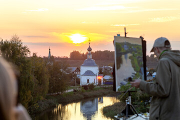Suzdal, Vladimir region, Russia, Golden Ring - View of the ancient Russian city from a height. The beautiful Kamenka River and the Church of the Epiphany on a summer evening.