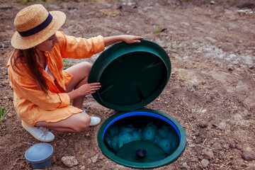 Woman checking autonomous sewage system lifting lid of plastic septic. Biological wastewater...