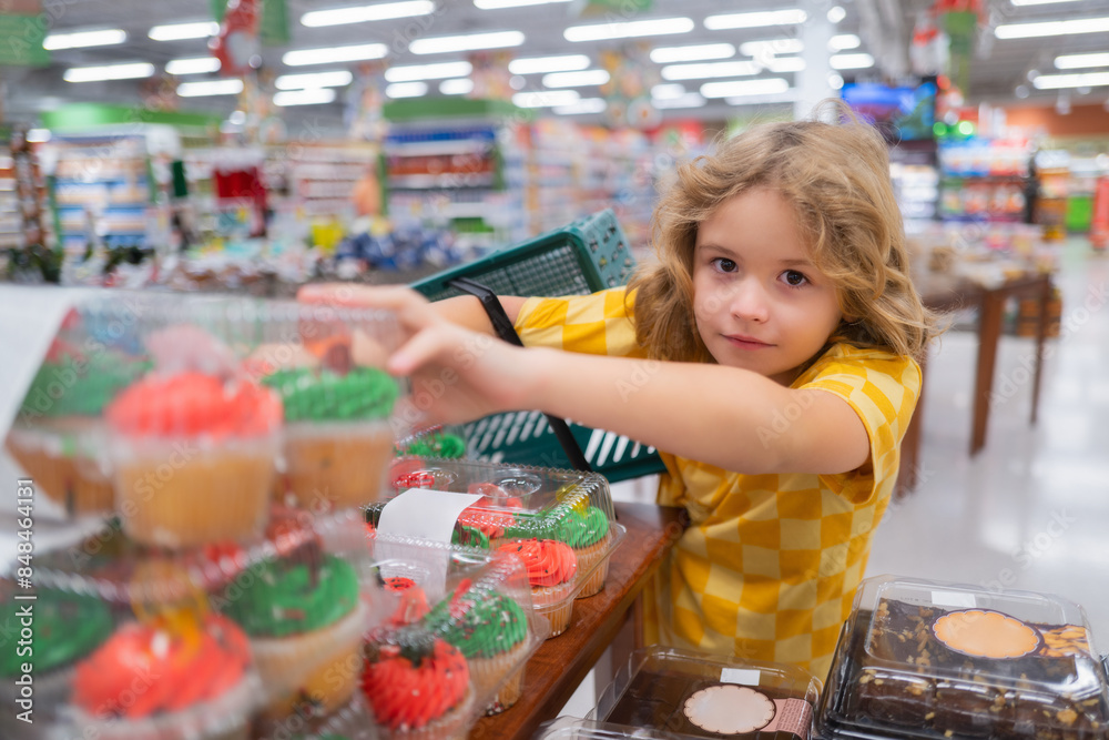 Wall mural Kid choosing cakes, cupcake muffin. Little kid going shopping.