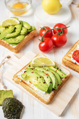 Sliced avocado on toast bread with spices on white wooden background. Food concept.