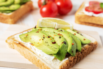 Sliced avocado on toast bread with spices on white wooden background. Food concept.