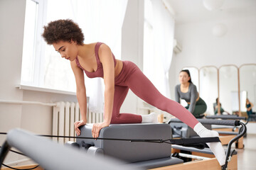 Young women in cozy attire practicing pilates in a gym together.