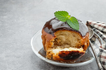 Rum baba decorated with dark chocolate on gray background