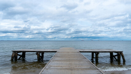 Obraz premium A serene wooden pier in Sopot, Poland, stretches into the Baltic Sea at sunrise, bathed in the soft, golden light of the early morning.