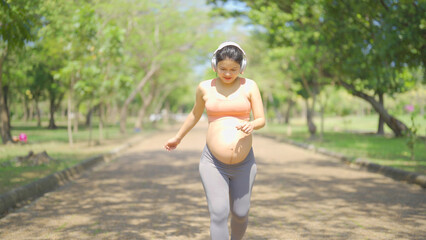 A portrait of happy Asian pregnant woman in yoga class club doing exercise at public garden park. Outdoor sport and recreation. activity with nature trees view. Having a baby. Family people lifestyle.