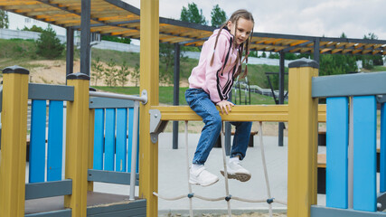 A cute little girl is playing in the children's yard. Healthy summer fun for kids. Child girl...