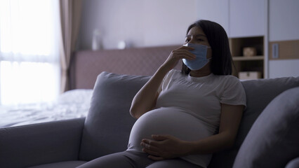 Depressed lonely Asian pregnant divorce woman with a mask for protecting covid-19 in bedroom at home. Having a baby. Family people lifestyle. Mom. quarantine