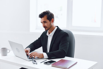 Fototapeta premium Man in office businessman sitting at desk and working in laptop, finance and startup concept, working lifestyle in bright office.