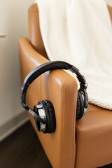 Black headphones hanging on the arm of a tan chair