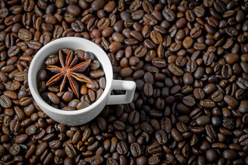 Arabica coffee beans background pattern texture white coffee cup with anise. Coffee cup with beans on black background. Top view arabica & robusta dark beans in cup background for cafe or coffee shop