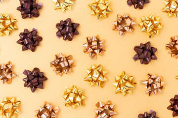 Bows made from metallic ribbons scattered on a golden background.