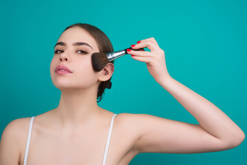 Obraz premium Girl hold blush blusher apply powder visage isolated over studio background. Woman powdering cheeks. Makeup brush. Female model gets blush powder on the cheekbones.