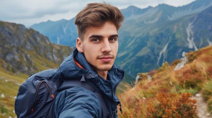 Naklejka premium Man taking a selfie in a mountainous landscape wearing a blue jacket