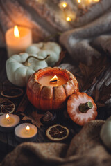 Atmospheric candle - shape of pumpkins, autumn decor on grey fall rainy day. Autumn cozy home atmosphere and inspiration, hygge concept. Aromatherapy, warming, relaxation. Wooden background