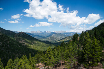 Valley with mountains below blue sky with clouds