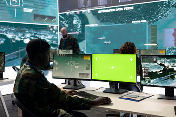 Army personnel monitors isolated green screen and surveillance footage, gathering important...