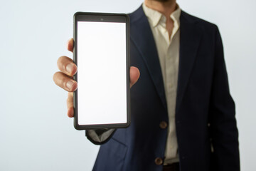 man in dark blue blazer holds show blank white smartphone screen, business marketing ad concept